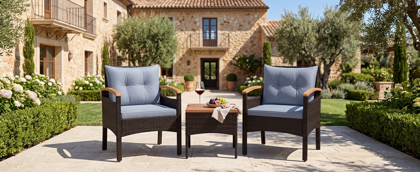 Ensemble de mobilier de jardin extérieur dans un jardin paysager comprenant deux fauteuils rembourrés bleu foncé avec des cadres en bois marron et une petite table d'appoint, un bâtiment en pierre et des arbres en arrière-plan.