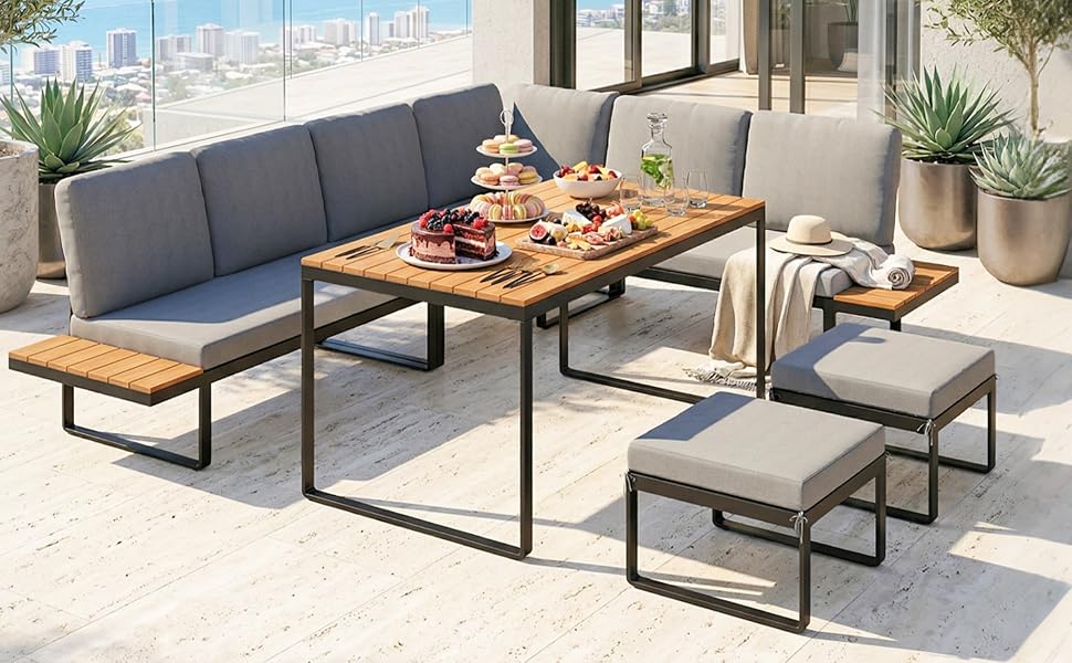 Ensemble de mobilier de jardin avec table supérieure en bois, structure en métal, canapé d'angle noir avec coussins, chaises assorties et bancs disposés sur une surface en béton avec des plantes.