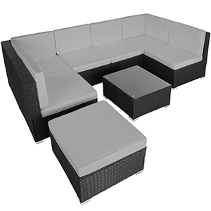 avec structure tissée foncée et coussins clairs. Comprend une pièce d'angle, deux sections latérales, une table basse et un pouf. Mobilier de jardin moderne.