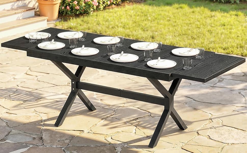 Ensemble de table à manger d'extérieur avec base en X noir et surface supérieure foncée, présentée sous plusieurs angles sur un patio en pierre. Le tableau semble contenir des espaces pour plusieurs paramètres de lieu.