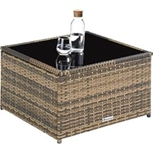avec base en rotin tressé et plateau en verre noir. Une bouteille d'eau et un verre sont placés à la surface pour donner du contexte.