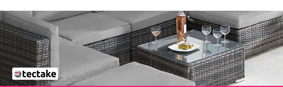 avec canapé en osier tressé, chaises et table en verre. Matériau en rotin gris avec coussins et verres à vin sur la table.