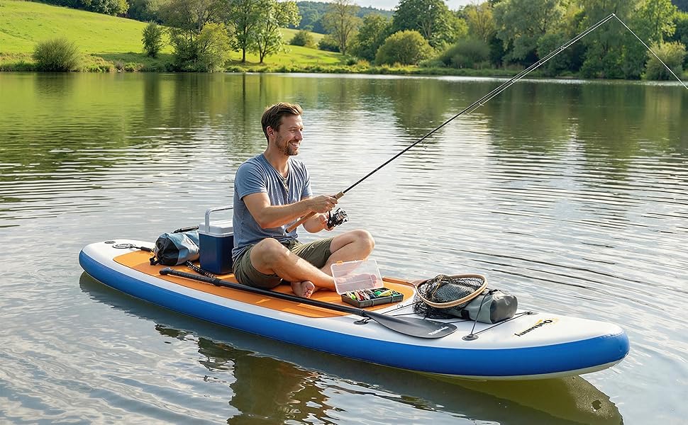 Homme faisant du kayak sur un kayak bleu sur une rivière avec une canne à pêche, des montagnes et une végétation verte visibles en arrière-plan pendant la journée.