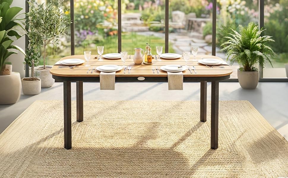 Aménagement de salle à manger moderne avec table en bois, suspensions en rotin naturel, plantes en pot et tapis texturé dans un espace intérieur ensoleillé.