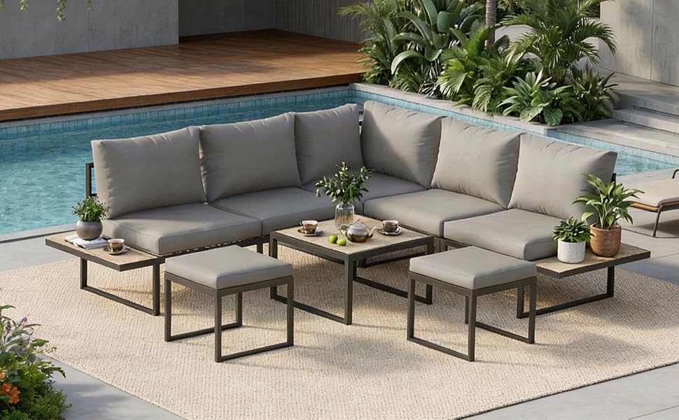 Ensemble de mobilier d'extérieur moderne avec coussins gris comprenant des sections de canapé modulaires et des tables basses assorties avec des cadres en métal noir. Cadre au bord de la piscine avec plantes décoratives.