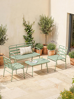 Ensemble de meubles de patio d'extérieur comprenant des chaises et une table en métal vert menthe, disposés sur un sol en carrelage en pierre avec des plantes en pot.