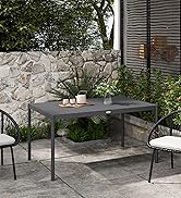 Terrasse extérieure avec table à manger rectangulaire foncée, chaises en métal, table d'appoint blanche, entourée de feuillage vert et mur de pierre.