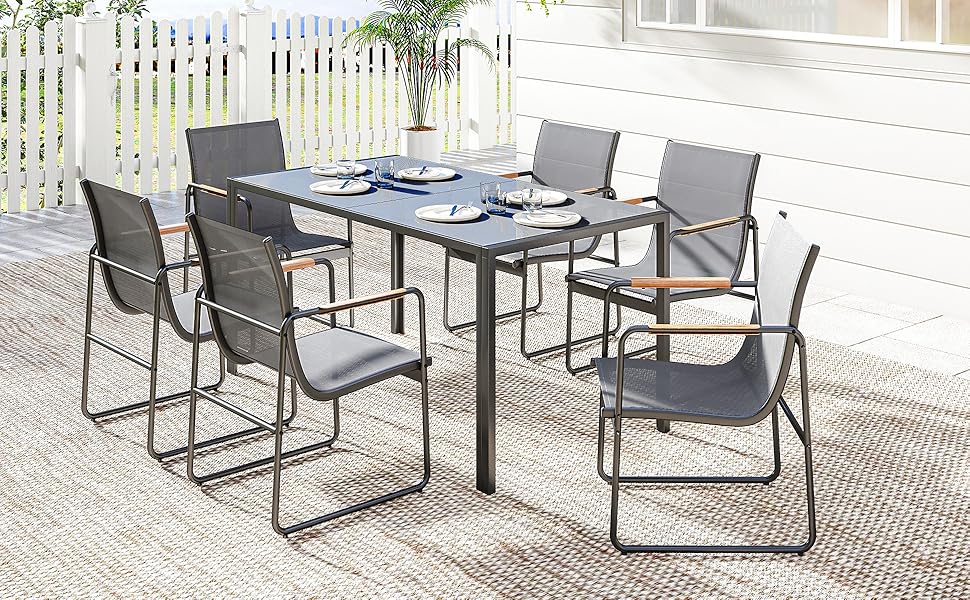 Ensemble de mobilier de jardin comprenant une table à manger moderne et plusieurs chaises en maille grise assorties sur une surface en pierre ou en béton.