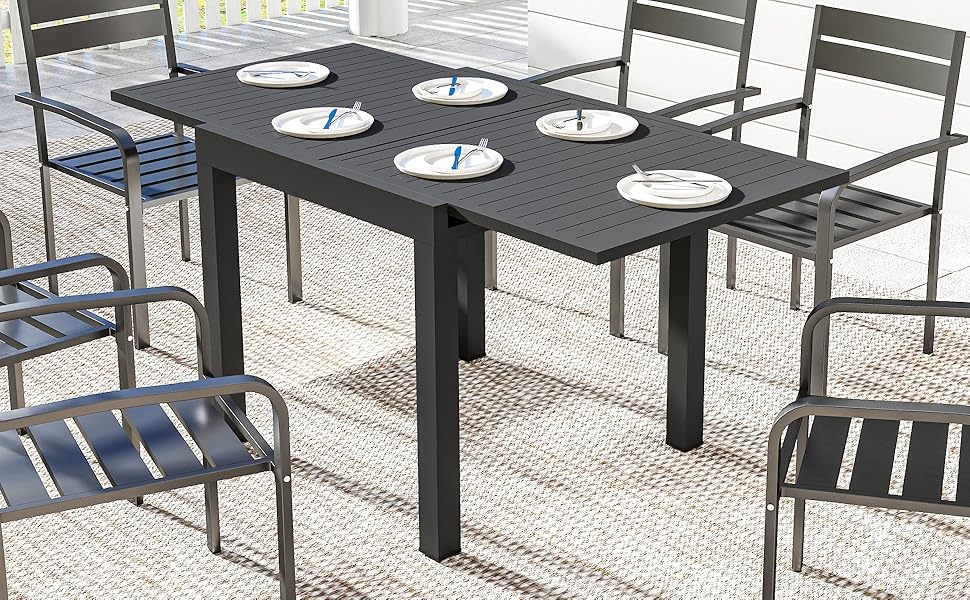Ensemble de salle à manger d'extérieur comprenant une table et des chaises en métal gris foncé sur une surface en pierre ou en béton. Design de mobilier de patio minimaliste contemporain.