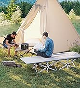 Deux personnes campent à l'extérieur avec une tente en toile beige, une personne debout à l'extérieur et une à l'intérieur, positionnées près d'une table de camping pliante.