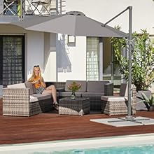 Terrasse extérieure avec mobilier en osier, comprenant un canapé et une table basse, sous un grand parasol en porte-à-faux. Terrasse en bois près d'une piscine.