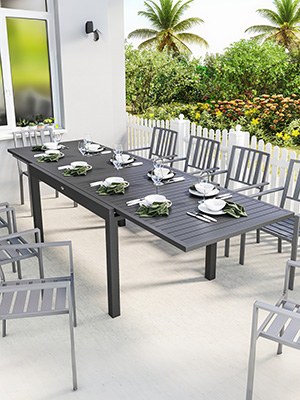 Ensemble de salle à manger pour terrasse extérieure comprenant une longue table rectangulaire avec plusieurs chaises, présentée dans une terrasse lumineuse ornée de plantes tropicales.