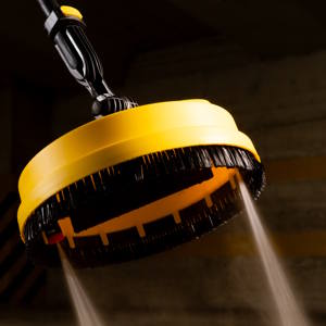 Pommeau de douche circulaire jaune pulvérisant de l'eau, photographié sur fond sombre avec un éclairage spectaculaire montrant des gouttelettes d'eau.