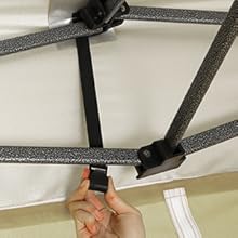 Des sangles noires ajustables à la main sont fixées à une surface blanche, peut-être à un drap de lit ou à un coin de couvre-matelas.