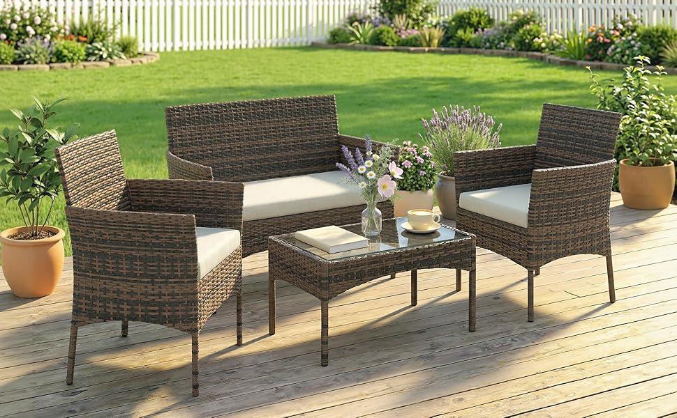 Meubles de conversation extérieurs en rotin tressé sur une terrasse en bois avec fond de pelouse verte. Chaises en osier brun foncé avec coussins et table en verre.