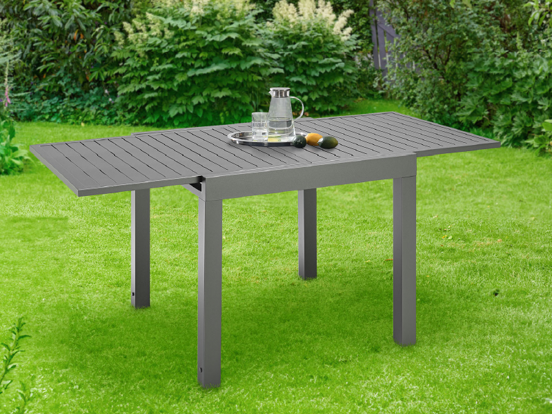 en aluminium gris, exposée sur la pelouse avec couverts. Dispose d'un dessus à lattes et de pieds robustes