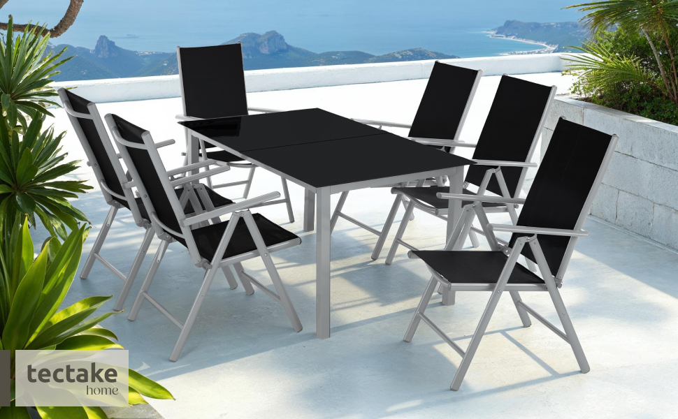 Le texte indique « tectake ». Ensemble de salle à manger extérieur avec table en verre noir et six chaises pliantes aux cadres argentés, positionnés sur la terrasse au bord de l'eau.