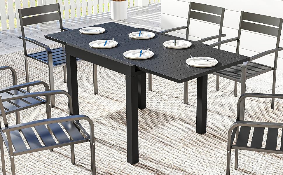 Ensemble de salle à manger d'extérieur moderne comprenant une table rectangulaire gris foncé et des chaises à lattes assorties. Ensemble de table avec assiettes blanches dans le cadre d'une terrasse.