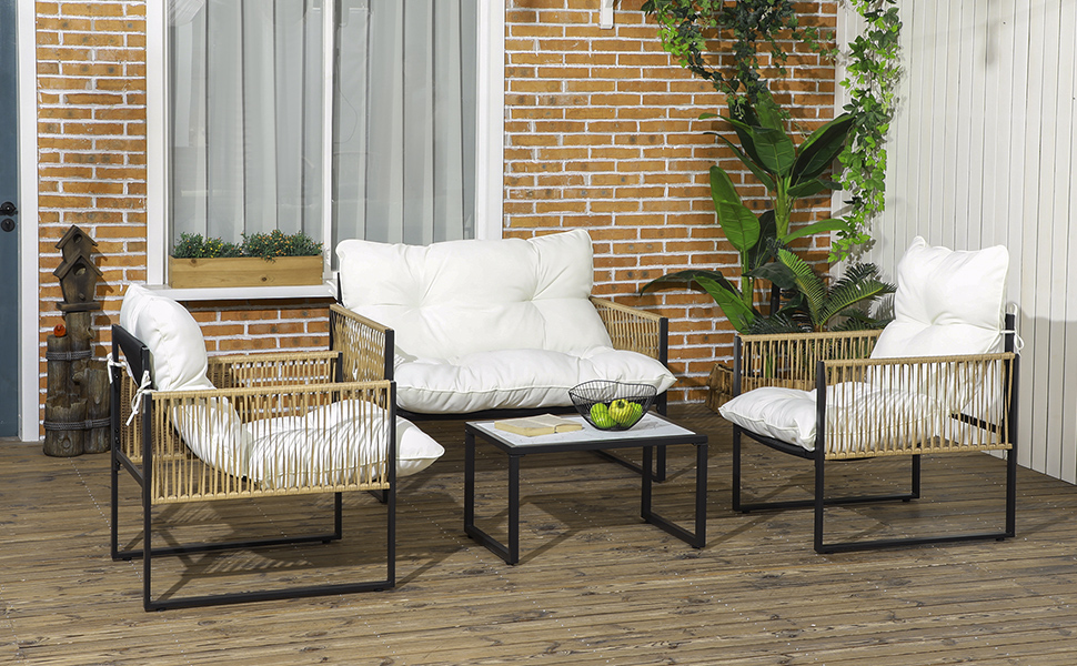 avec deux chaises, une causeuse et une table basse. Tissage beige façon corde sur armatures en métal noir. Coussins blancs Situé sur une terrasse en bois contre un mur de briques.