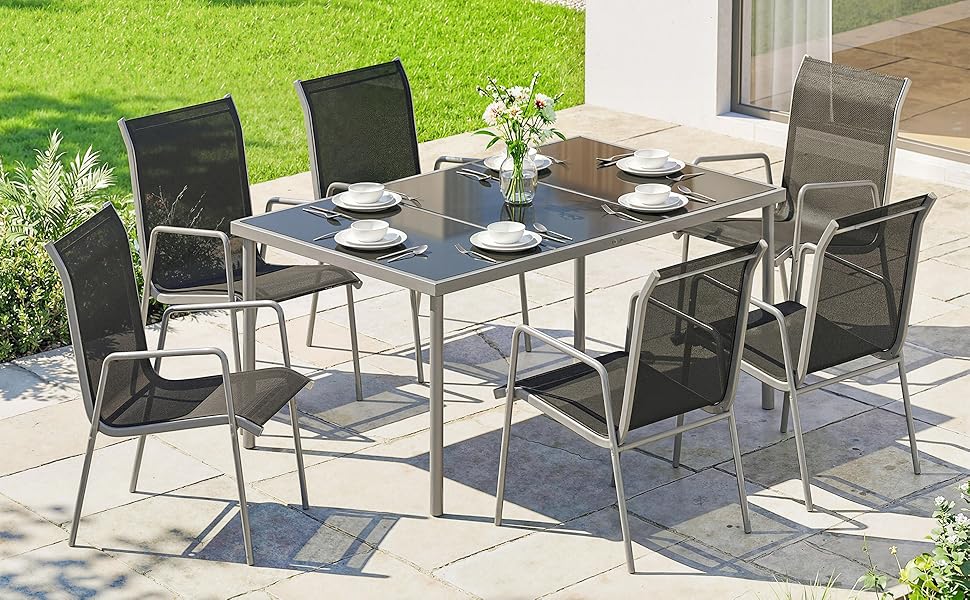 Ensemble de mobilier de patio extérieur comprenant une table à manger avec plateau en verre et six chaises en maille noire. Tapis d'extérieur à motifs bleus sur gazon. Arrangement de mobilier de jardin moderne.