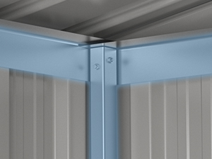Gros plan d'un joint d'angle métallique, probablement pour un cabanon ou une structure de stockage. Montre des pièces métalliques imbriquées formant une liaison solide entre les murs et le toit