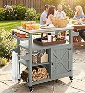 Chariot de jardin extérieur avec structure en métal blanc, étagère supérieure en composite gris avec surface de cuisson, étagères de rangement inférieures avec bois de chauffage, plusieurs personnes assises à la table derrière.