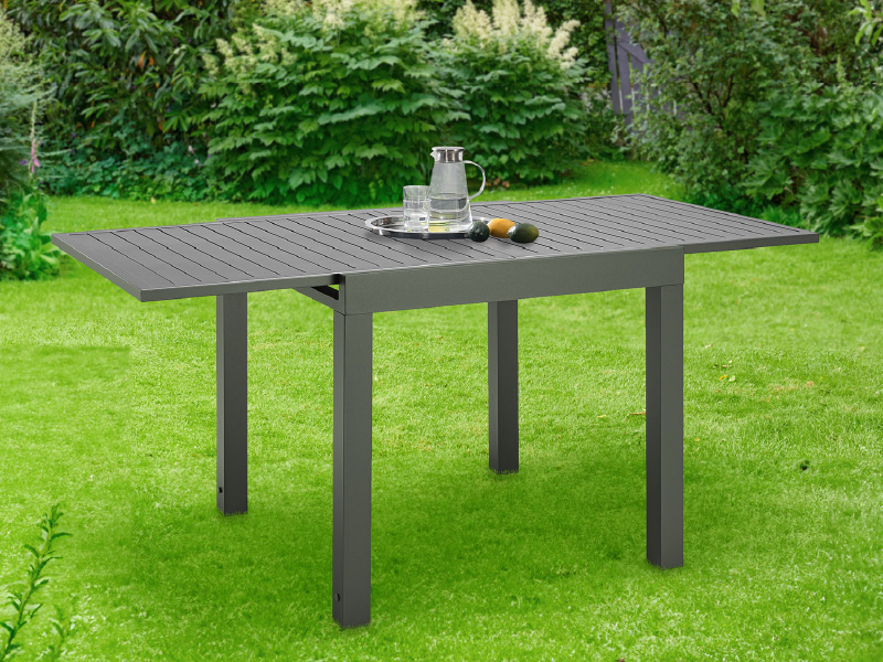 en gris foncé, photographiée dans un jardin. Dispose d'un dessus à lattes et d'une capacité d'extension