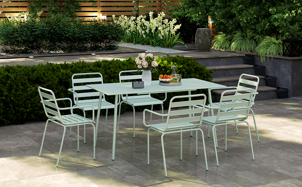 avec table en métal vert menthe et six chaises assorties, placé sur un patio entouré d'un jardin luxuriant.