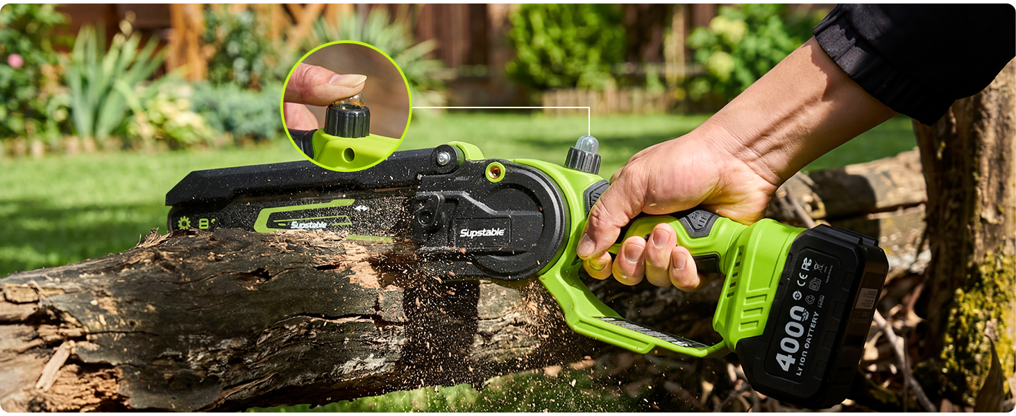 Personne utilisant une tronçonneuse verte alimentée par batterie pour couper une bûche tombée dans un jardin extérieur.