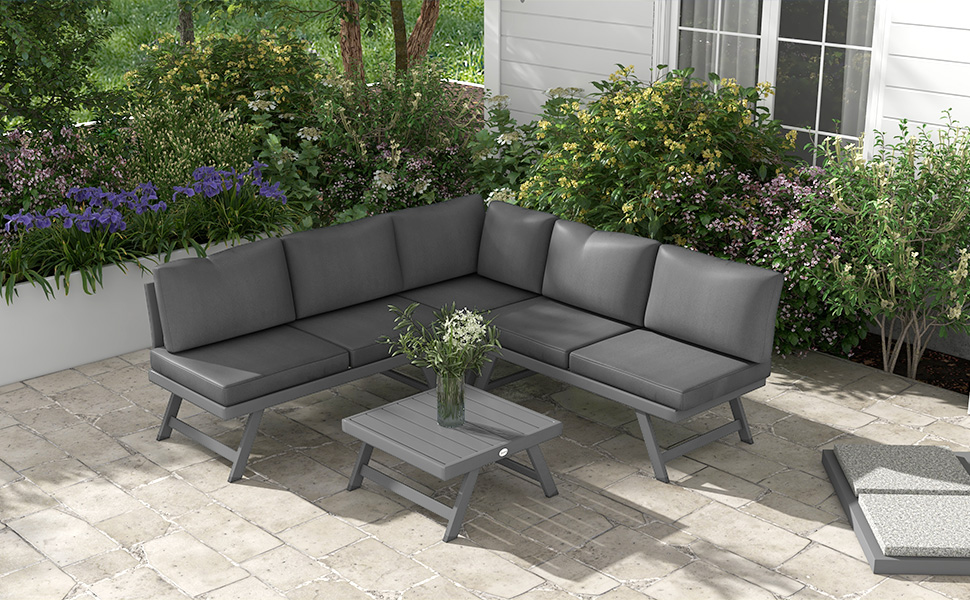 avec coussins gris et table basse assortie. Situé sur un patio en pierre entouré d'un jardin luxuriant.
