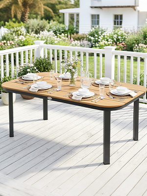 Table à manger d'extérieur avec structure en métal noir et plateau en bois naturel sur terrasse blanche. Table rectangulaire positionnée dans un jardin avec balustrade blanche et fond paysager visible.